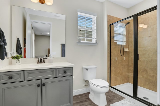 bathroom featuring hardwood / wood-style floors, a shower with shower door, vanity, and toilet