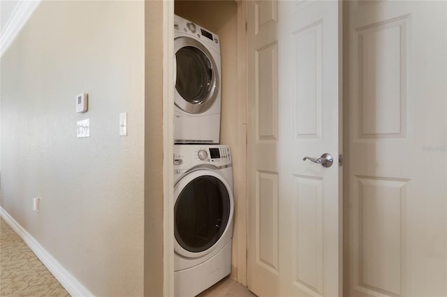 laundry room featuring stacked washer / drying machine and light colored carpet