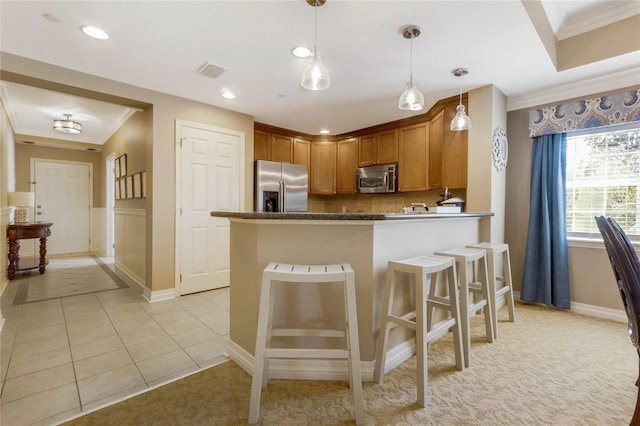 kitchen featuring kitchen peninsula, decorative light fixtures, light tile flooring, appliances with stainless steel finishes, and a breakfast bar