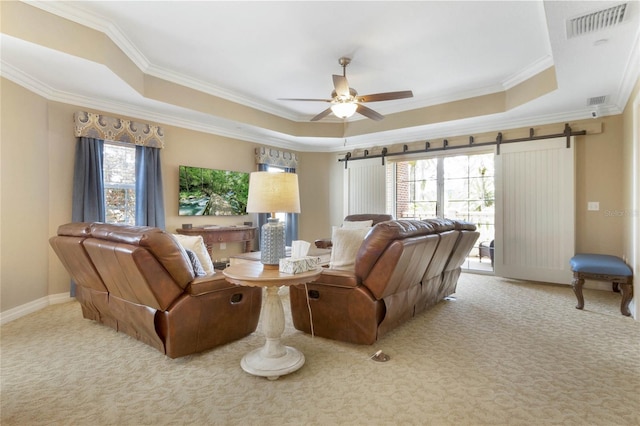 living room with ceiling fan, a barn door, light carpet, a raised ceiling, and crown molding