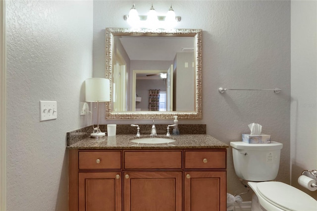 bathroom with toilet, ceiling fan, and vanity with extensive cabinet space