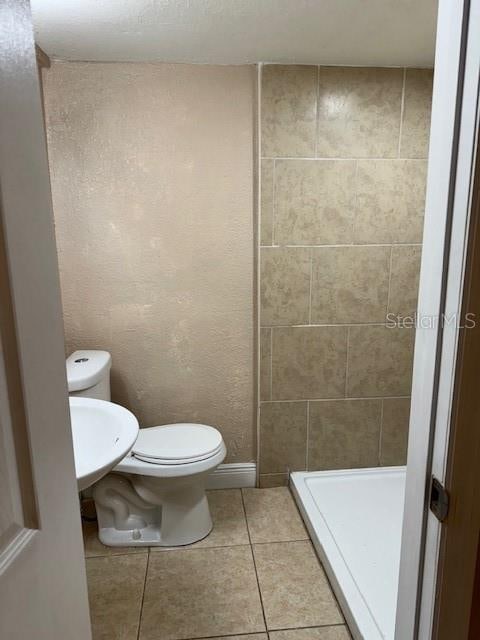 bathroom featuring toilet, tile flooring, and sink