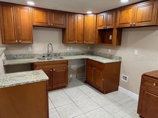 kitchen featuring light stone countertops, sink, and light tile floors