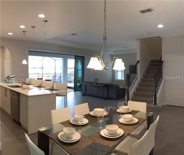 dining room with a notable chandelier, dark tile patterned floors, and sink