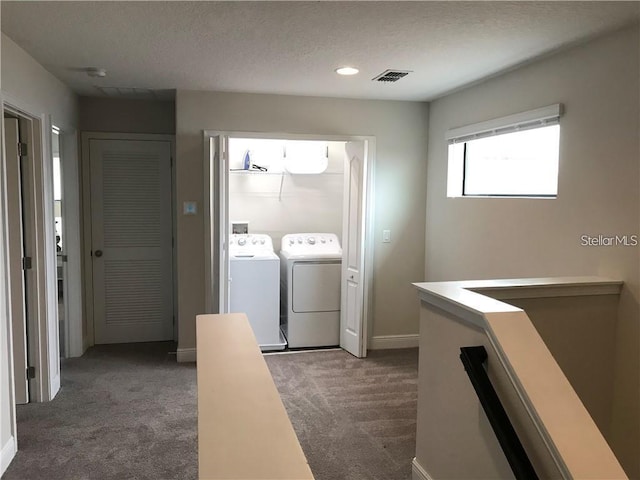 clothes washing area with dark carpet, washing machine and clothes dryer, and a textured ceiling