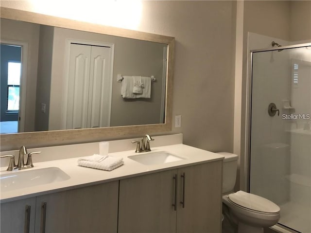 bathroom with toilet, vanity, and a shower with shower door