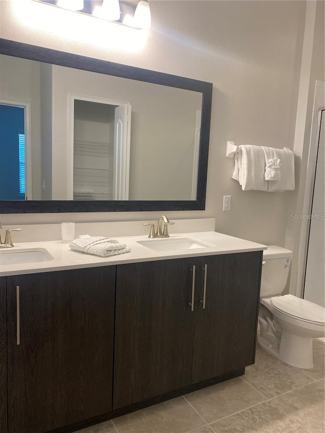 bathroom with toilet, vanity, and tile patterned floors