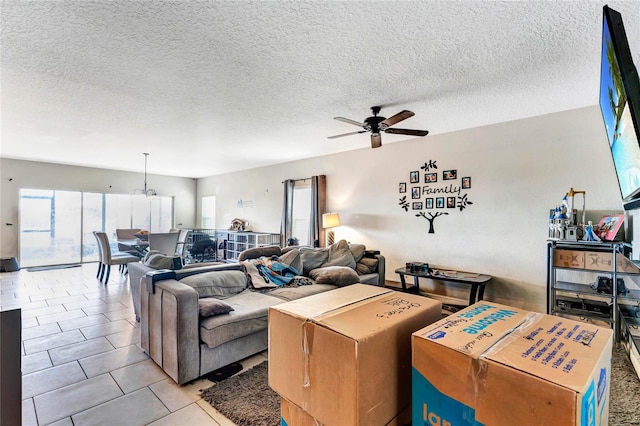 tiled living room featuring a textured ceiling and ceiling fan with notable chandelier