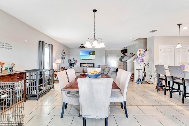 tiled dining room with ceiling fan with notable chandelier