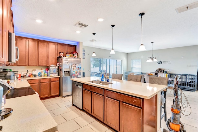 kitchen with pendant lighting, an island with sink, a kitchen bar, and sink