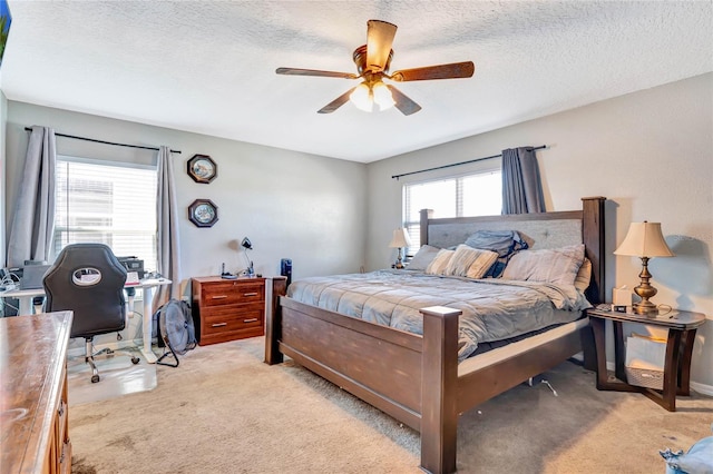 bedroom featuring light carpet, ceiling fan, and a textured ceiling