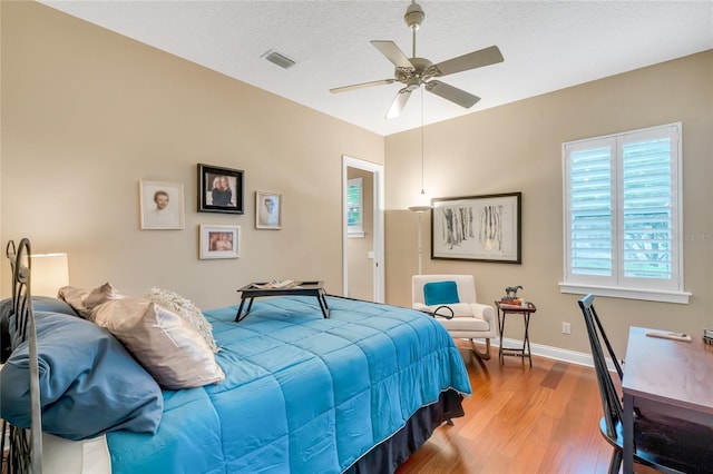 bedroom featuring a textured ceiling, ceiling fan, and wood-type flooring