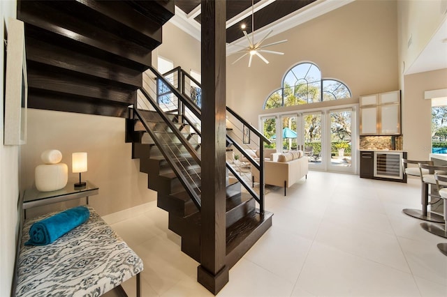 staircase with a high ceiling, tile patterned flooring, beam ceiling, and french doors