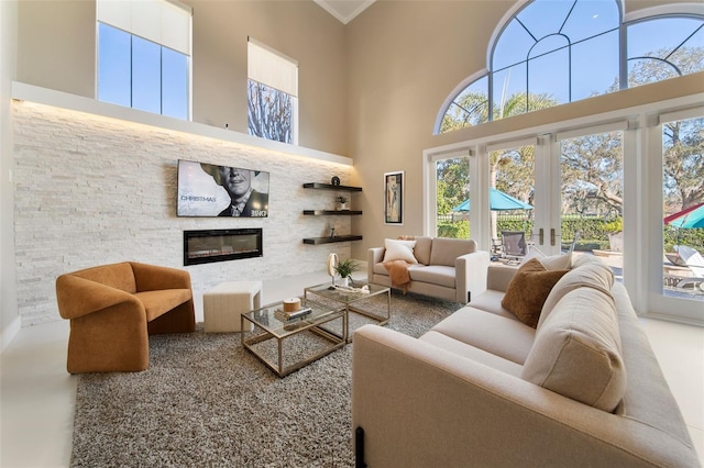 living room with crown molding, a towering ceiling, and a fireplace