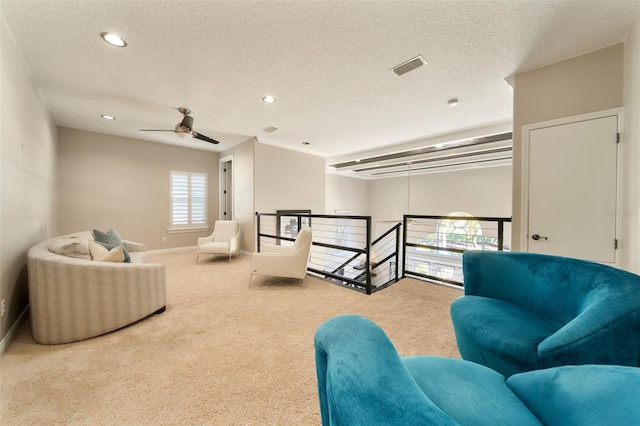 sitting room with a textured ceiling, ceiling fan, and carpet