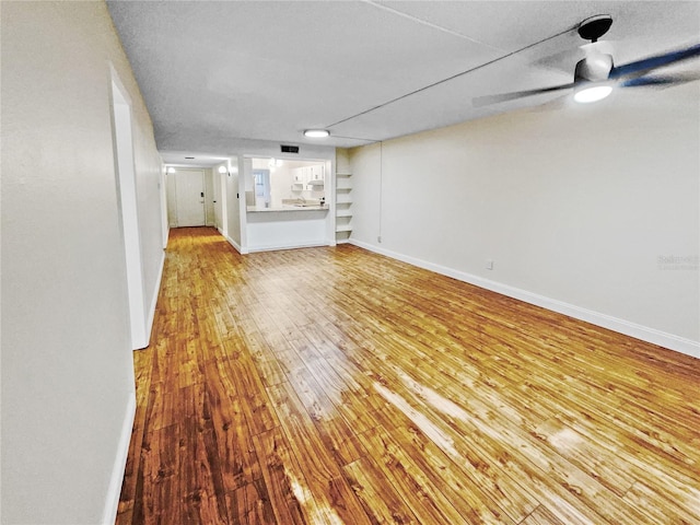 unfurnished living room featuring ceiling fan, light wood-type flooring, and a textured ceiling