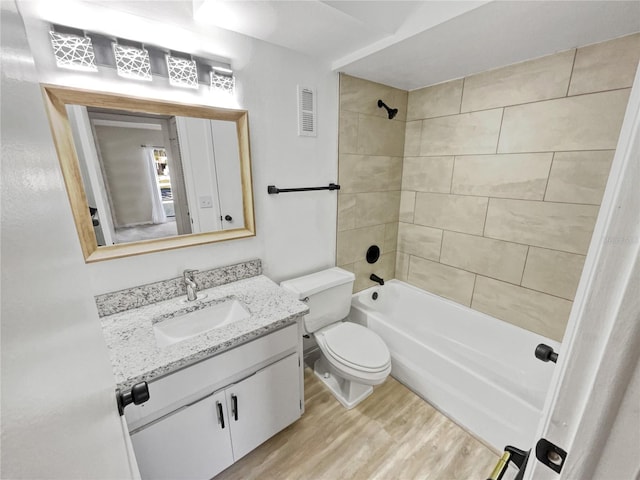 full bathroom featuring tiled shower / bath, hardwood / wood-style floors, vanity, and toilet