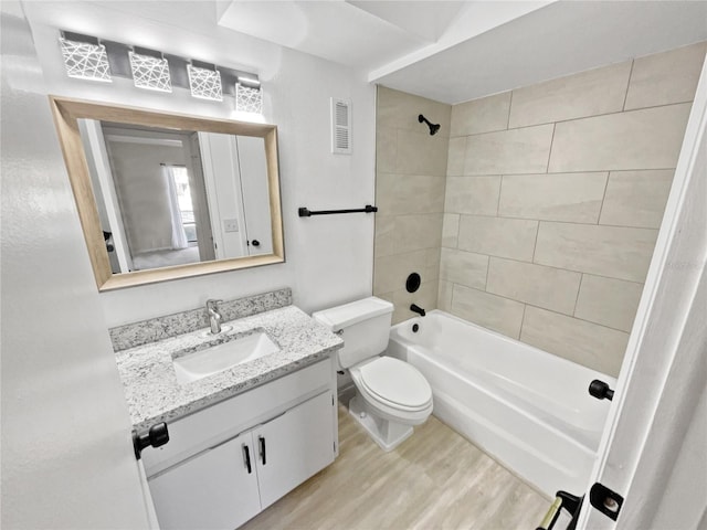 full bathroom with wood-type flooring, tiled shower / bath, vanity, and toilet