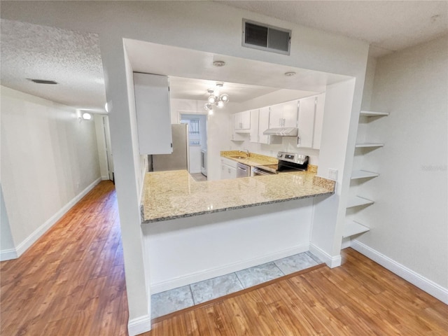 kitchen with light wood-type flooring, light stone counters, stainless steel appliances, kitchen peninsula, and white cabinetry