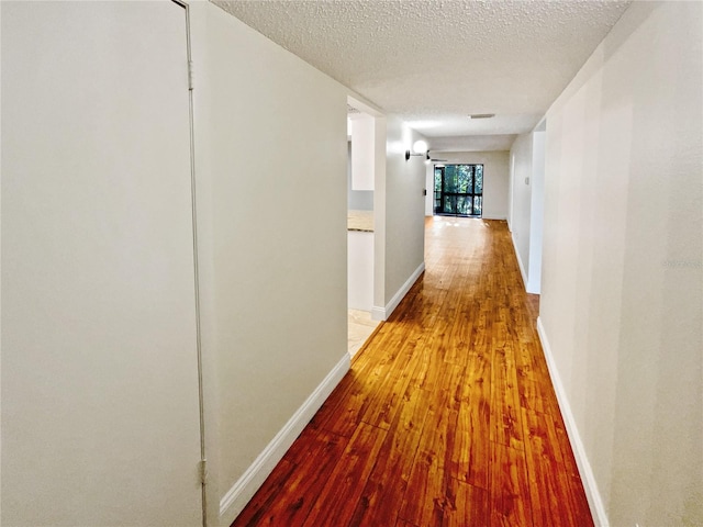 corridor featuring hardwood / wood-style flooring and a textured ceiling