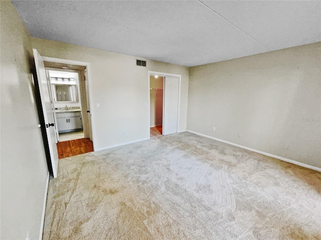 unfurnished bedroom featuring carpet floors, a textured ceiling, and connected bathroom