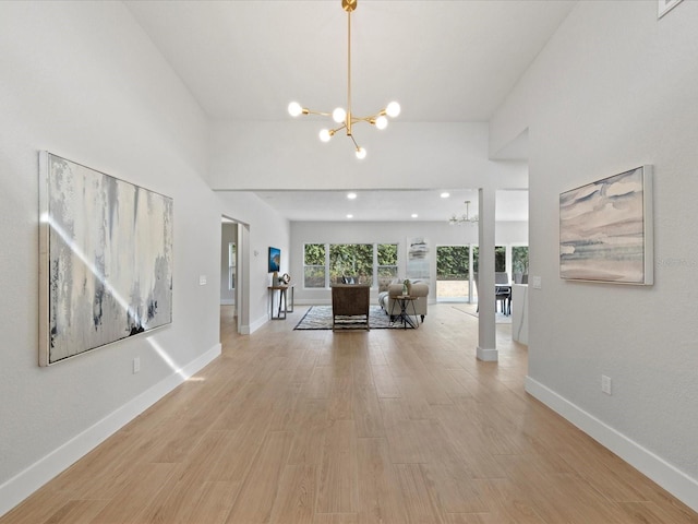 interior space featuring a towering ceiling, an inviting chandelier, and light hardwood / wood-style flooring