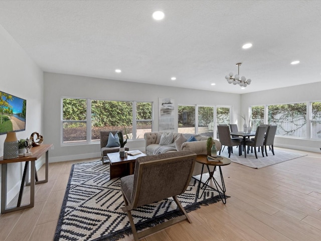 living room with an inviting chandelier, light hardwood / wood-style floors, and a textured ceiling