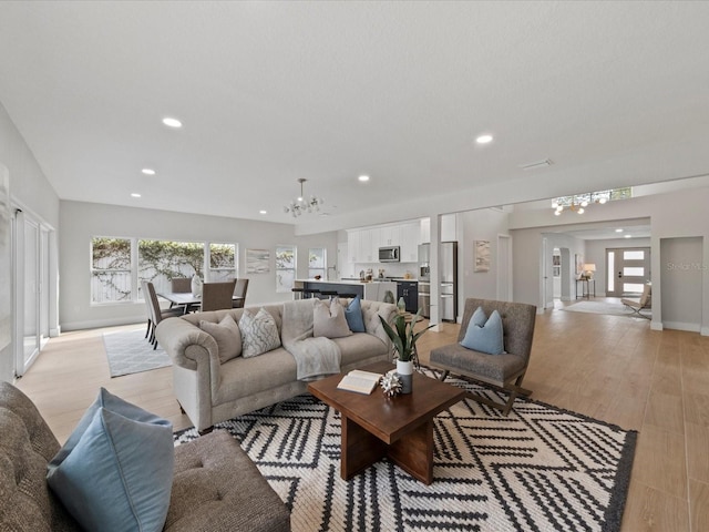 living room with an inviting chandelier and light hardwood / wood-style floors