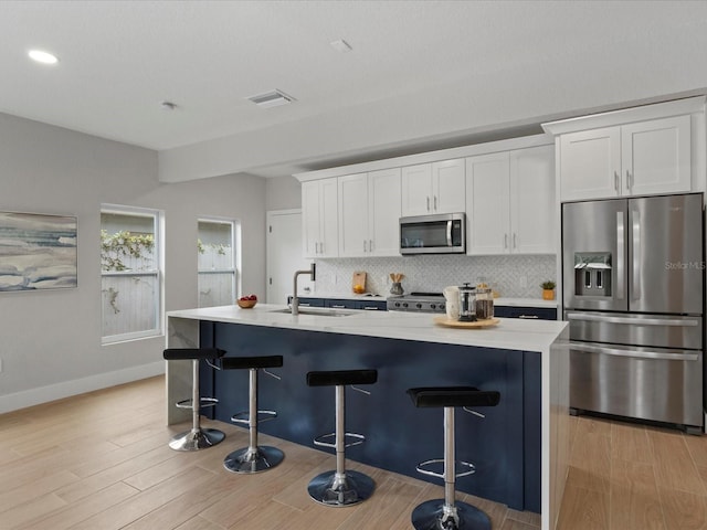 kitchen with white cabinets, light hardwood / wood-style floors, appliances with stainless steel finishes, and sink