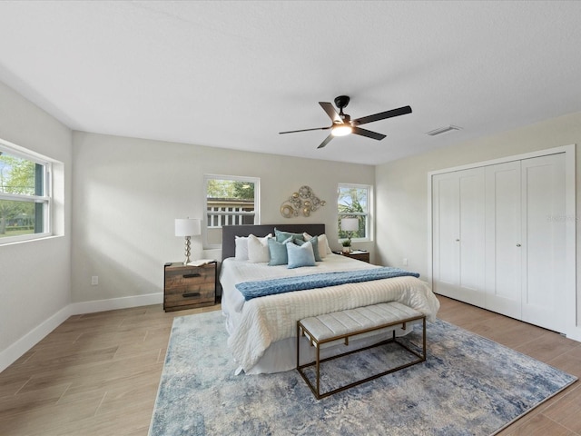 bedroom with light hardwood / wood-style flooring, ceiling fan, and multiple windows