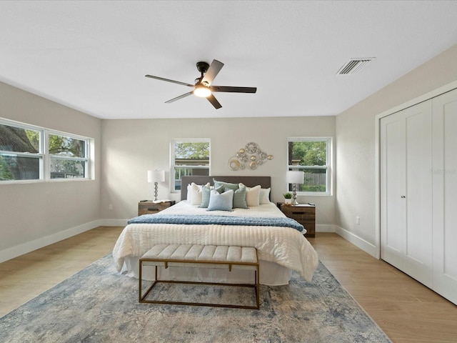 bedroom featuring ceiling fan, multiple windows, a closet, and light hardwood / wood-style flooring