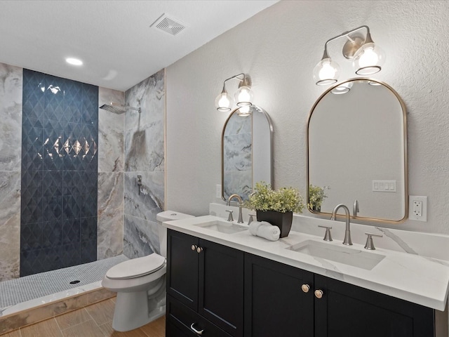 bathroom featuring toilet, double sink vanity, tiled shower, tile floors, and an inviting chandelier