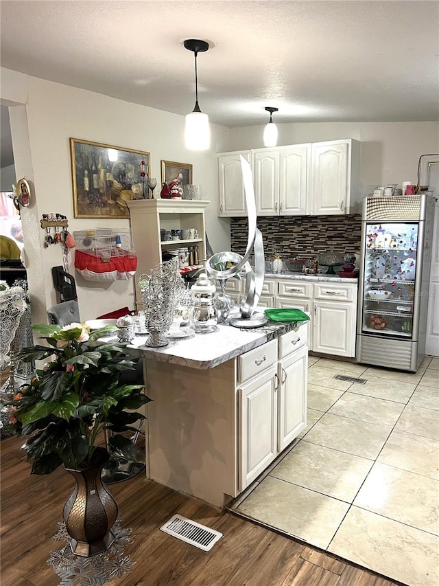 kitchen featuring decorative light fixtures, white cabinetry, backsplash, built in refrigerator, and light tile floors