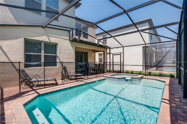 view of swimming pool with an in ground hot tub, glass enclosure, and a patio