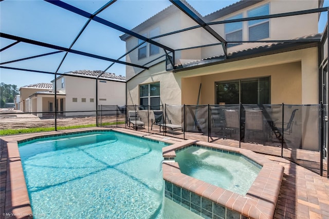 view of pool with a patio area, an in ground hot tub, and glass enclosure