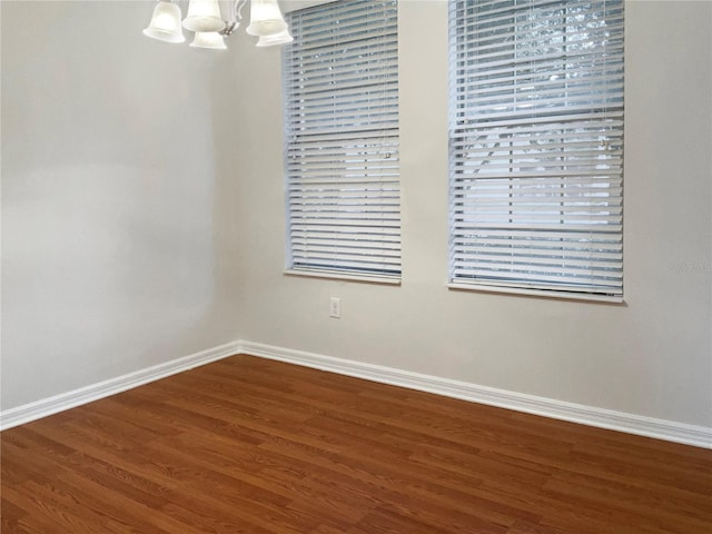 empty room featuring a notable chandelier, plenty of natural light, and hardwood / wood-style floors