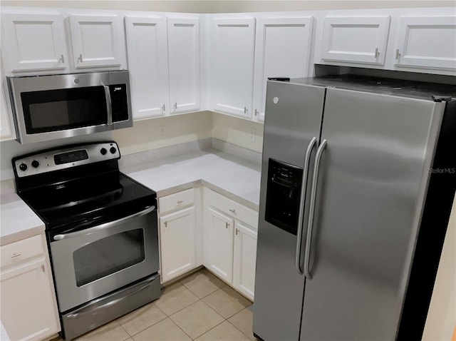 kitchen with light tile patterned floors, stainless steel appliances, and white cabinets