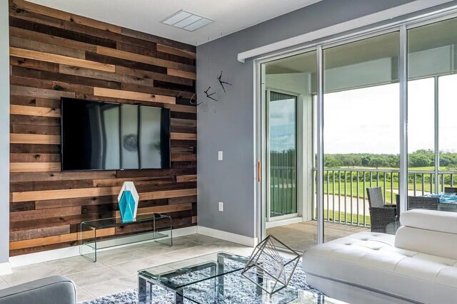 living room with wood walls, plenty of natural light, and light tile flooring