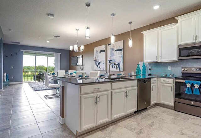 kitchen with hanging light fixtures, stainless steel appliances, white cabinetry, and an inviting chandelier