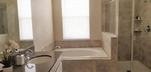 bathroom featuring large vanity and tiled tub