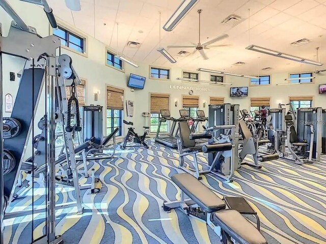 gym with a high ceiling, carpet, and ceiling fan