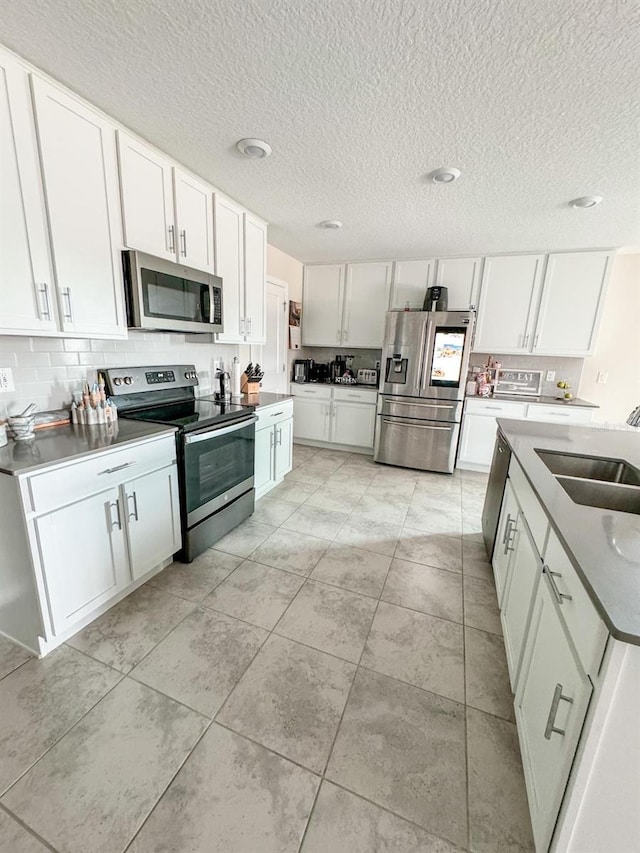 kitchen featuring light tile patterned floors, sink, white cabinetry, and appliances with stainless steel finishes