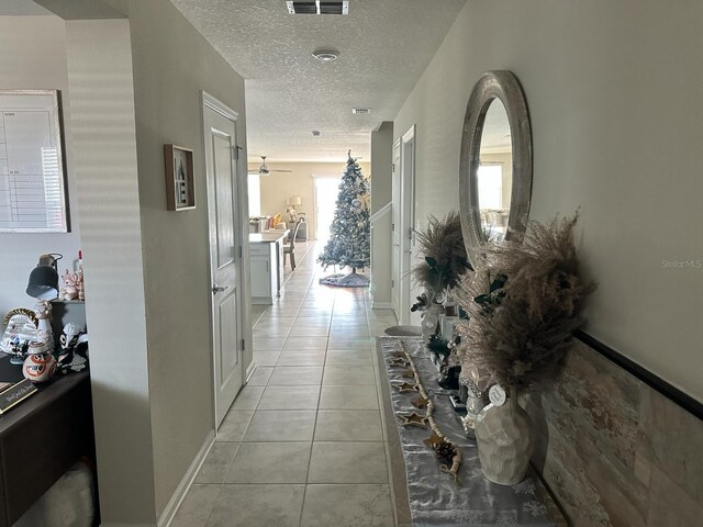 hall featuring a textured ceiling and light tile patterned floors