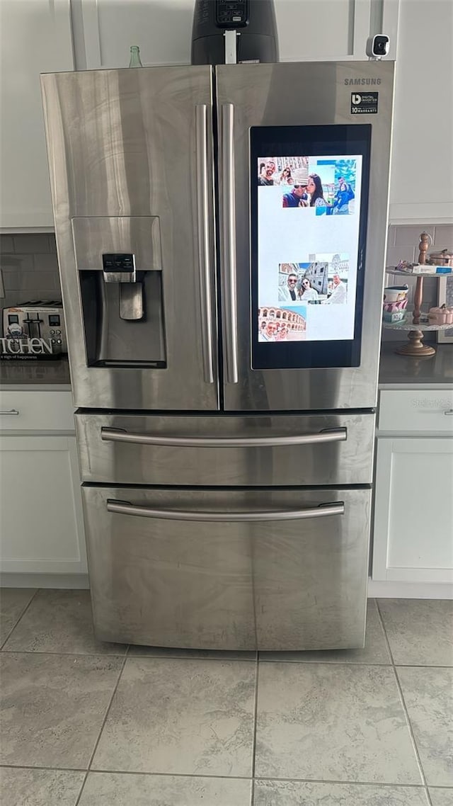 interior details featuring stainless steel refrigerator with ice dispenser and white cabinetry