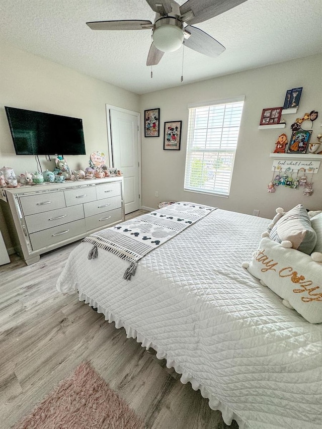 bedroom featuring ceiling fan, light hardwood / wood-style floors, and a textured ceiling