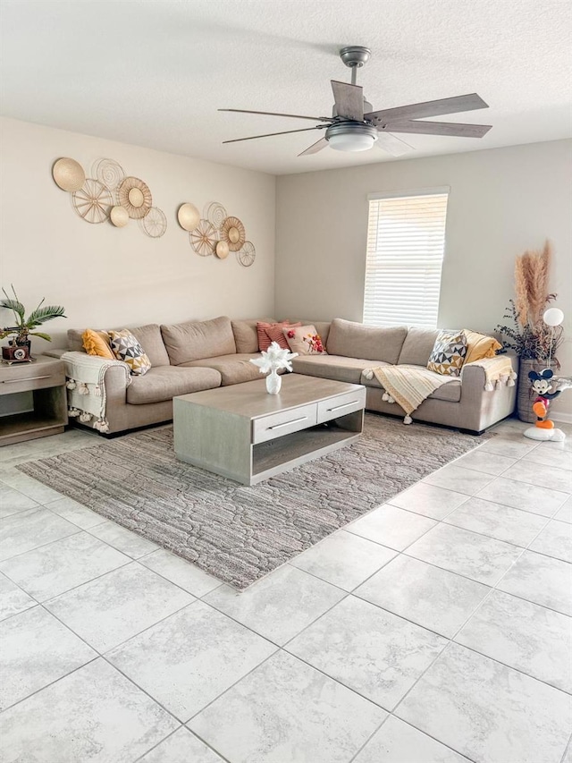 living room featuring a textured ceiling, light tile patterned floors, and ceiling fan