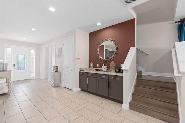 interior space featuring light stone countertops, dark brown cabinets, and light tile flooring