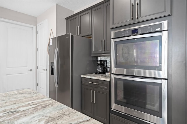 kitchen featuring tasteful backsplash, stainless steel appliances, and light stone counters