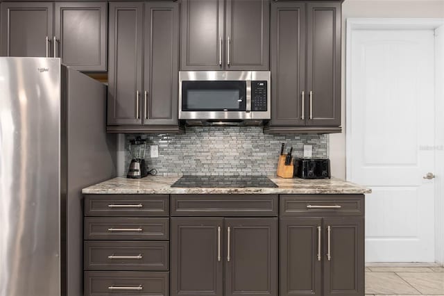 kitchen with light tile floors, light stone counters, tasteful backsplash, and stainless steel appliances