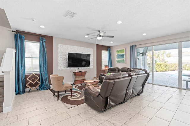 tiled living room with a textured ceiling and ceiling fan